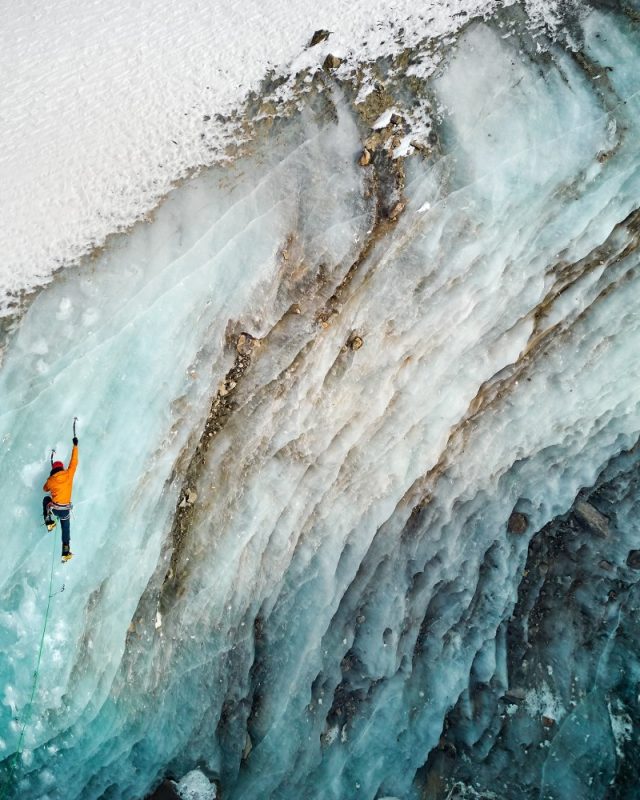 Aerial,Drone,View,Of,Athlete,In,Orange,Jacket,Ice,Climbing